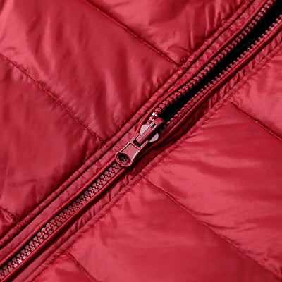 Gros plan sur une fermeture éclair rouge sur une veste matelassée. Mode hiver, vêtement chaud, textile rouge, détail couture.