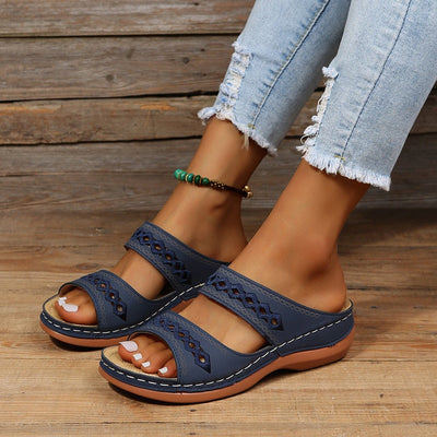 Sandales bleues pour femmes avec motifs ajourés, portées avec un jean déchiré. Chaussures d'été confortables, tendance et élégantes.