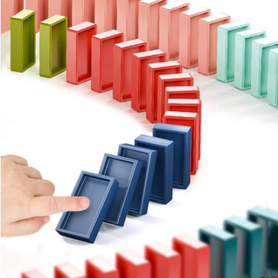Doigts d'enfant poussant des dominos colorés en cascade, dégradé de couleurs vives, jeu de dominos, effet domino, jouet éducatif.