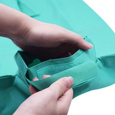 Deux mains tiennent un sac en tissu vert avec une poignée renforcée. Sac de rangement pliable, idéal pour l'organisation à domicile.