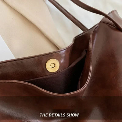 Sac à main en cuir marron avec bouton-pression doré, design élégant et moderne, parfait pour la mode féminine et le style quotidien.