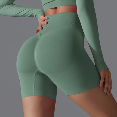 Femme en tenue de sport verte, leggings taille haute, accentuant la silhouette. Mode fitness, vêtements de sport confortables et tendance.
