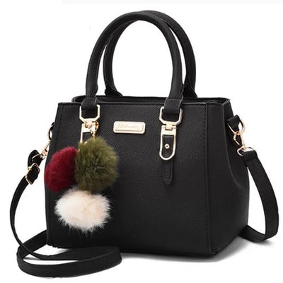 Sac à main noir élégant avec bandoulière, décoré de pompons colorés. Accessoire mode femme, cuir synthétique, style chic et moderne.