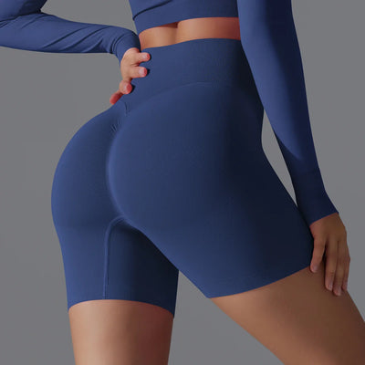 Femme en tenue de sport bleue moulante, mettant en valeur des shorts taille haute. Mode fitness, vêtements de sport tendance, style athlétique.