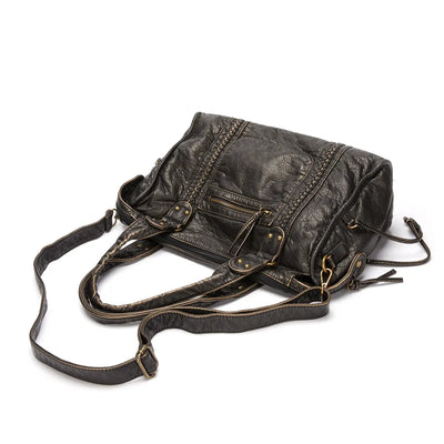 Sac à main en cuir noir avec bandoulière réglable, poches zippées et détails en métal doré vieilli. Accessoire mode élégant et pratique.