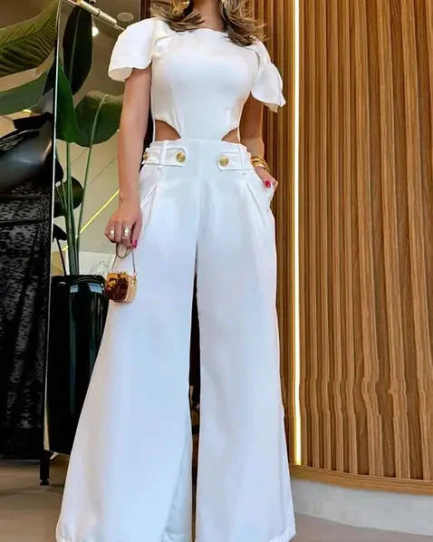 Femme en combinaison blanche élégante avec découpes latérales, manches bouffantes, tenant un petit sac à main. Mode chic, tendance, style moderne.