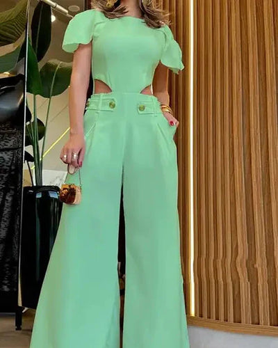 Combinaison verte élégante avec manches courtes et découpes latérales, portée par une femme. Mode tendance, tenue chic, style moderne.