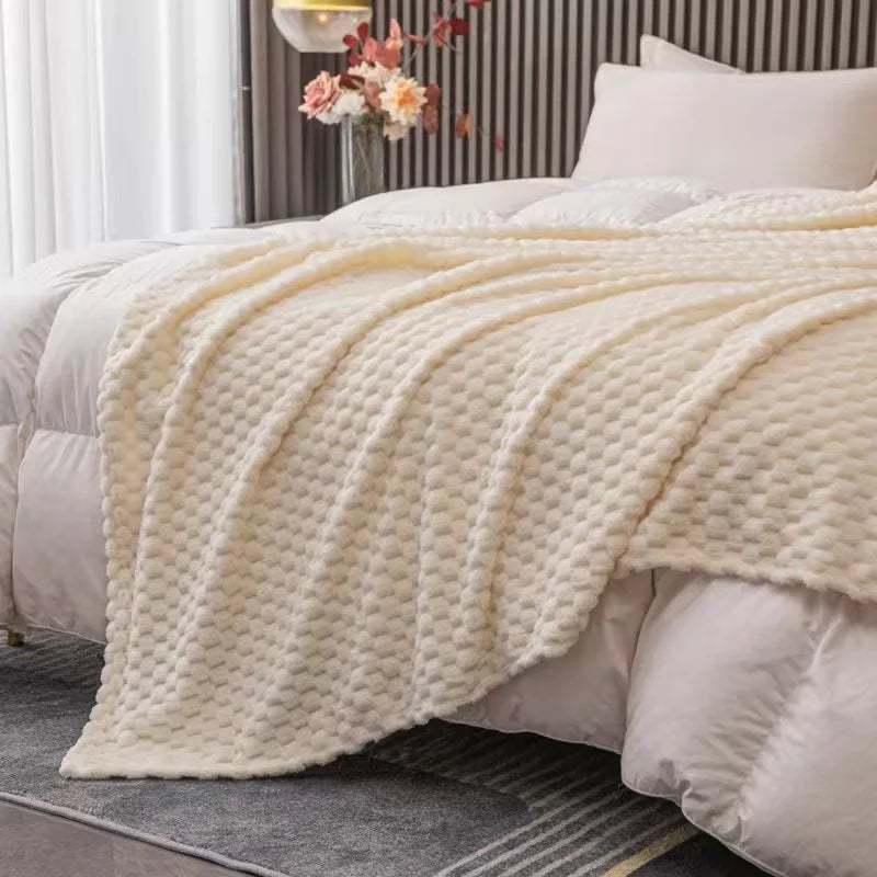 Lit avec couverture texturée en laine beige, chambre moderne, décoration élégante, lumière naturelle, ambiance chaleureuse et confortable.