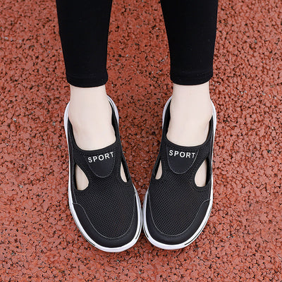 Chaussures de sport noires pour femmes sur fond rouge, design respirant avec découpes, semelle blanche, idéales pour la marche et le fitness.