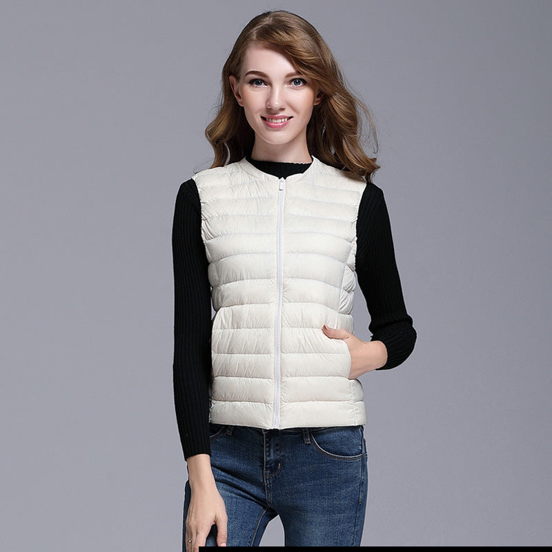 Femme portant un gilet matelassé blanc, manches longues noires, jeans bleus. Mode automne, style décontracté, tendance féminine.