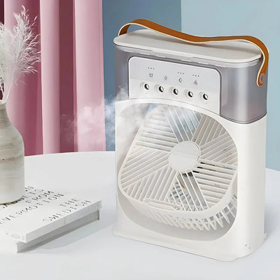 Ventilateur portable blanc avec poignée en cuir, fonction brumisateur, posé sur une table blanche près d'un vase et d'un livre, rideaux roses en arrière-plan.