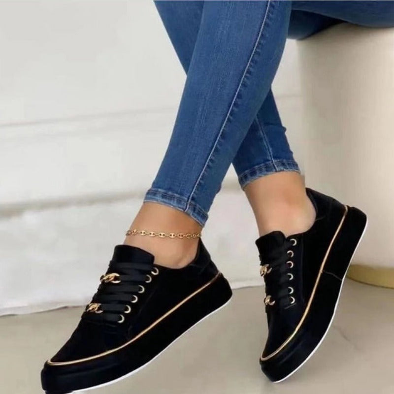 Chaussures noires élégantes avec détails dorés portées avec un jean bleu. Sneakers tendance pour femme, style décontracté et moderne.