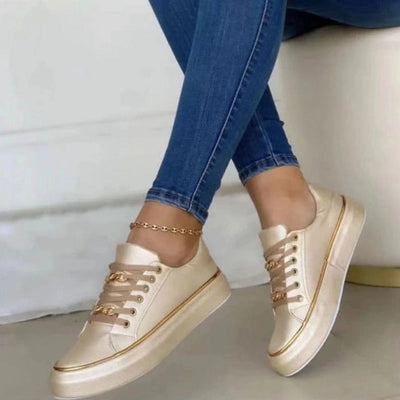 Chaussures dorées élégantes portées avec un jean bleu, posées sur un sol clair. Sneakers tendance pour femme, style moderne et chic.