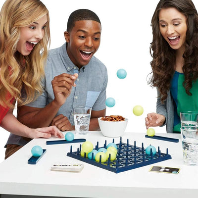 Trois personnes jouent à un jeu de société Bounce-Off, lançant des balles colorées sur une grille. Jeu de société amusant, compétition, convivialité.