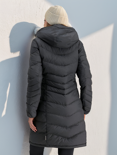 Femme portant un manteau d'hiver noir matelassé avec capuche, vue de dos, contre un mur blanc. Mode hiver, vêtements chauds, style urbain.
