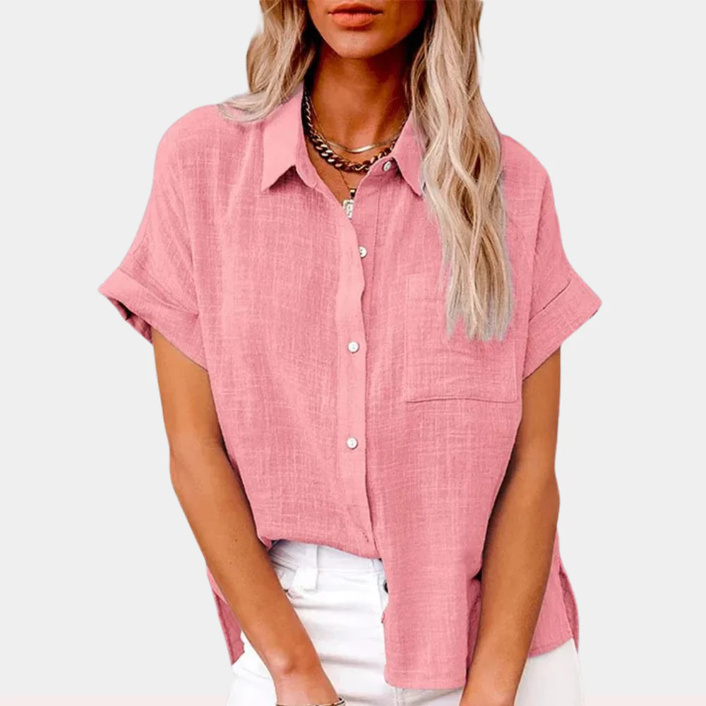 Chemisier rose en lin pour femme, manches courtes, col classique, boutons blancs, porté avec un pantalon blanc. Mode féminine élégante et décontractée.