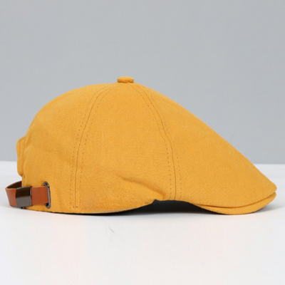 Casquette plate jaune moutarde en tissu, vue de côté, avec sangle réglable en cuir marron. Accessoire de mode tendance et élégant.