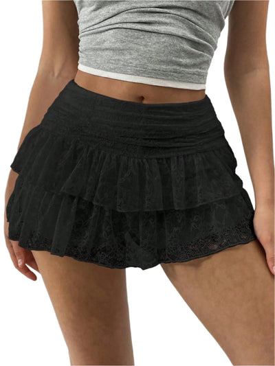 Femme portant une jupe noire à volants en dentelle, taille haute, avec un haut gris. Mode féminine, style élégant et tendance.