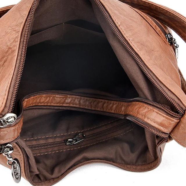 Sac à main en cuir marron ouvert, montrant plusieurs compartiments zippés et une doublure intérieure. Accessoire mode femme élégant et pratique.