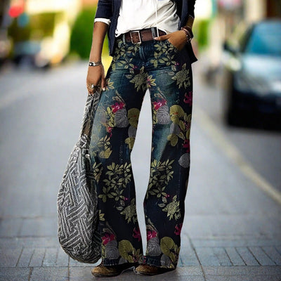 Pantalon large à motifs floraux porté par une femme dans la rue, avec un sac à main en tissu gris. Mode urbaine, style décontracté, tendance.