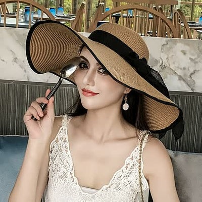 Femme élégante avec chapeau de paille large, robe en dentelle blanche, tenant une cuillère, assise dans un café moderne. Mode estivale chic.