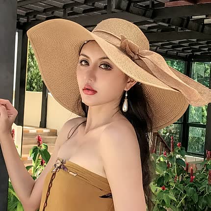 Jeune femme portant un chapeau de paille élégant avec un large bord et un nœud, posant dans un jardin ensoleillé. Mode estivale, accessoire chic.