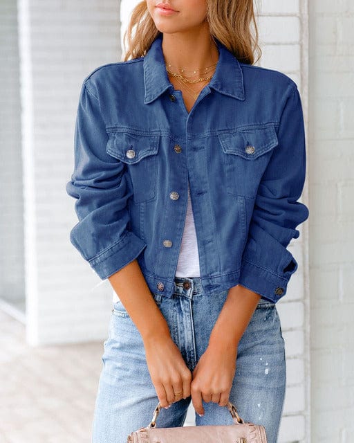 Femme portant une veste en jean bleu, manches retroussées, avec un t-shirt blanc et un jean clair. Mode décontractée, tendance vestimentaire.