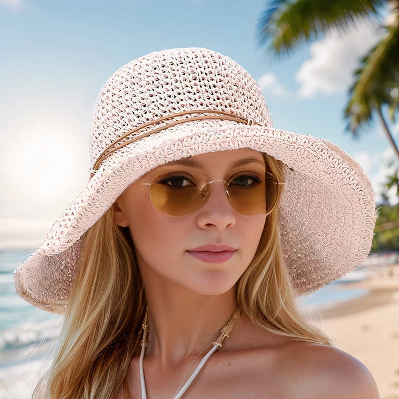 Femme portant un chapeau de paille élégant et des lunettes de soleil sur une plage tropicale, ciel bleu et palmiers en arrière-plan.