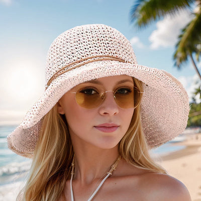 Femme portant un chapeau de paille élégant et des lunettes de soleil sur une plage tropicale, ciel bleu et palmiers en arrière-plan.