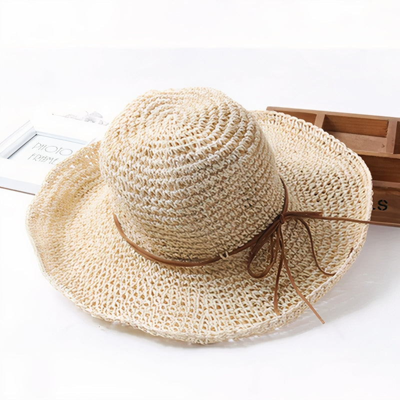 Chapeau de paille tressé beige avec ruban en cuir marron, idéal pour l'été et la plage. Accessoire mode femme tendance et élégant.
