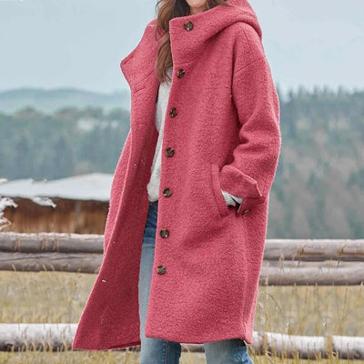Femme portant un manteau rose en laine bouclée avec capuche, debout en extérieur. Mode hiver, style décontracté, tendance vêtements chauds.