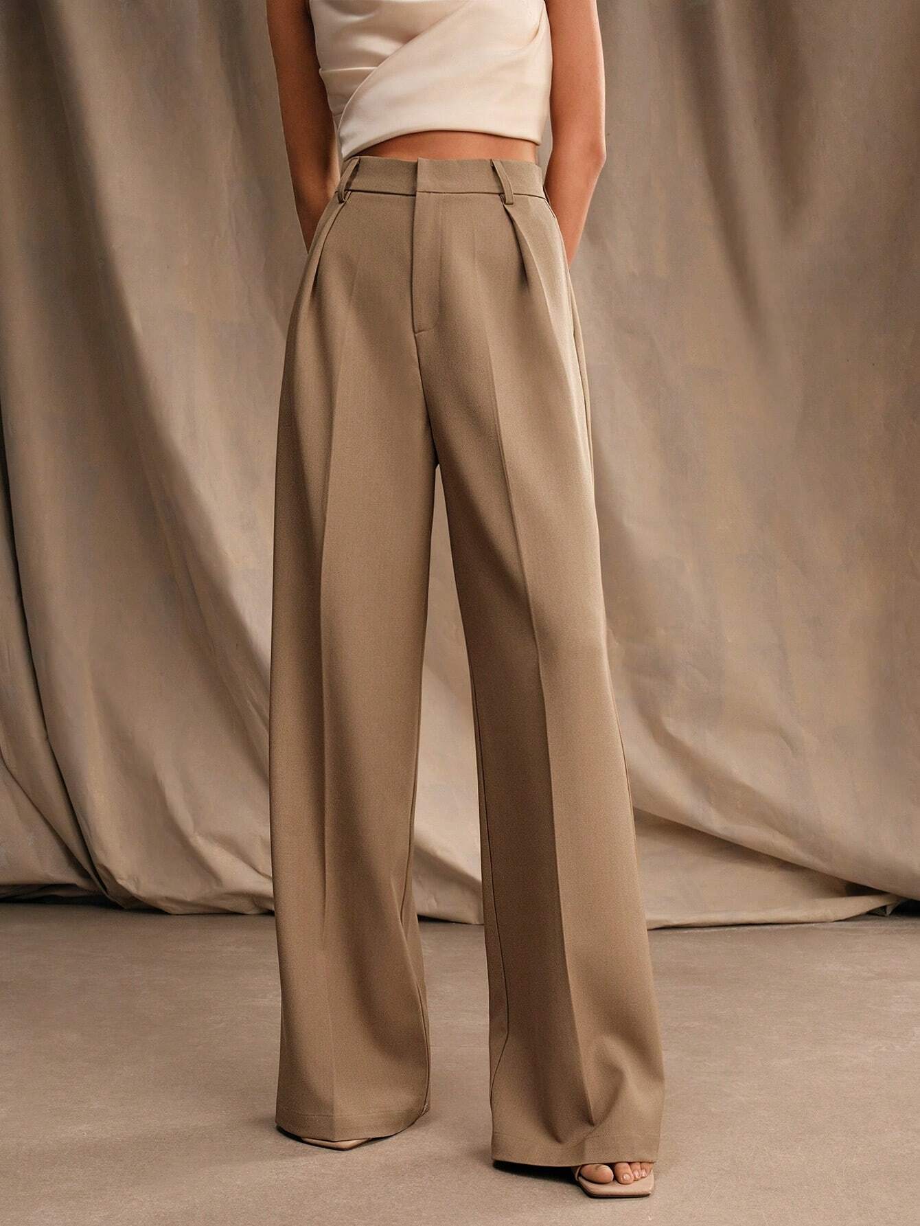 Pantalon large beige femme, taille haute, élégant, avec poches, porté avec un haut blanc sans manches. Mode chic, tendance automne.