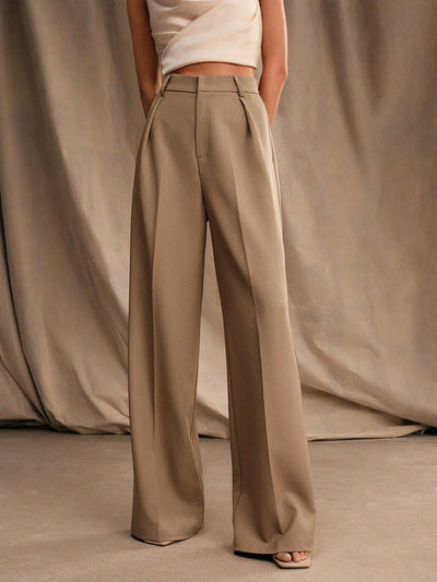 Pantalon large beige femme, taille haute, élégant, avec poches, porté avec un haut blanc sans manches. Mode chic, tendance automne.