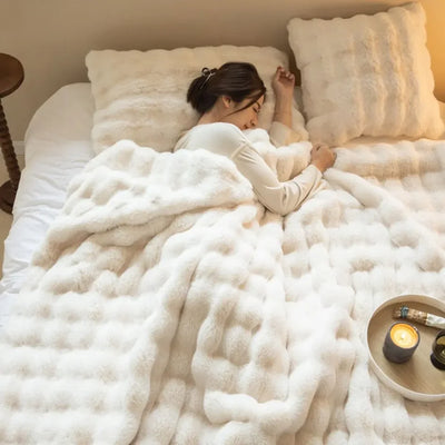 Femme dormant paisiblement sous une couverture en fausse fourrure blanche, avec oreillers assortis, dans une chambre cosy. Ambiance chaleureuse et relaxante.