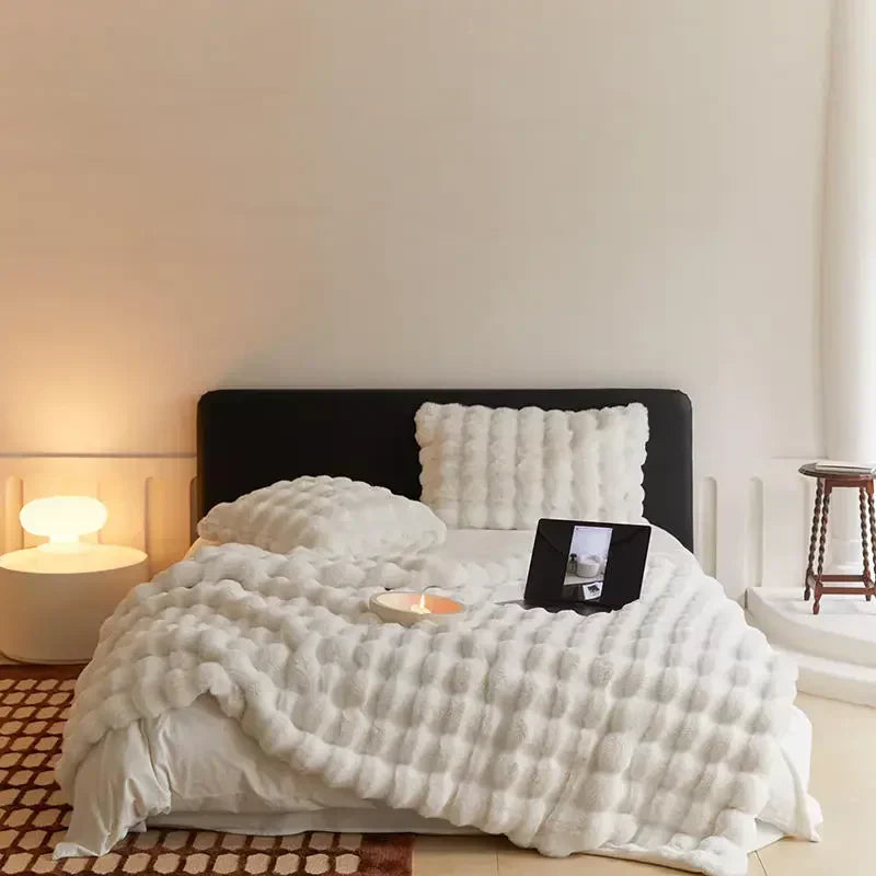 Lit moderne avec couverture texturée blanche, oreillers assortis, tablette sur le lit, lampe design sur table de chevet, intérieur minimaliste.