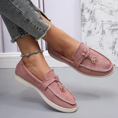 Chaussures mocassins roses pour femme, en tissu, portées avec un jean gris déchiré. Accessoire: bracelet de cheville turquoise. Mode décontractée.