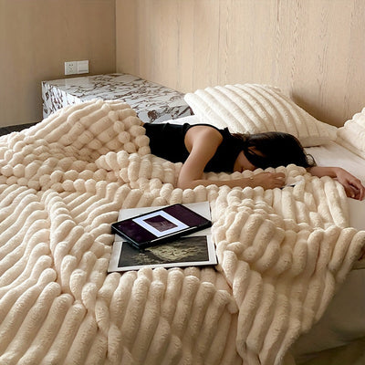 Femme dormant sur un lit avec couverture en fausse fourrure beige, tablettes posées à côté, chambre moderne. Confort, détente, technologie.