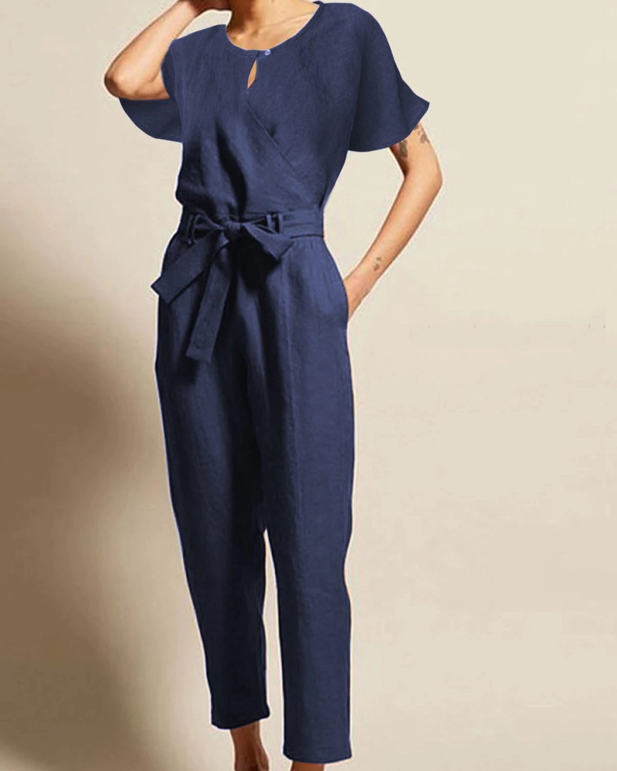 Combinaison bleu marine élégante pour femme, manches courtes, ceinture à nouer, style décontracté chic, fond beige.