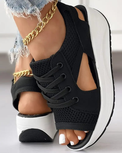 Sandales noires à plateforme avec lacets, portées avec un jean déchiré et bracelet chaîne doré. Mode estivale, chaussures tendance femme.