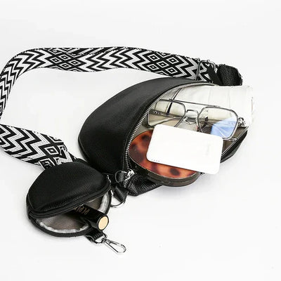 Sac banane noir avec bandoulière à motifs géométriques, contenant lunettes, smartphone, rouge à lèvres et comprimés. Accessoire mode pratique.