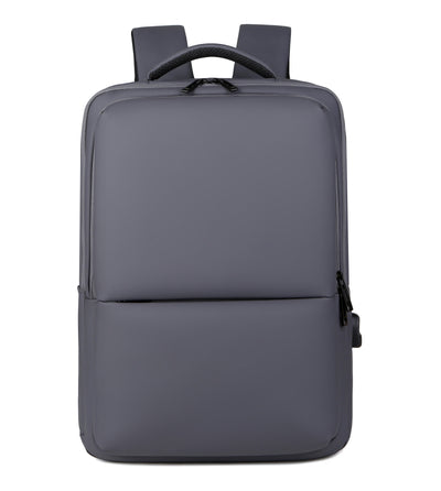 Sac à dos gris moderne et minimaliste, avec bretelles rembourrées, poche avant zippée, idéal pour ordinateur portable et usage quotidien.