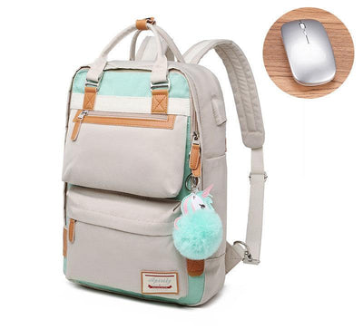 Sac à dos beige et vert menthe avec porte-clés licorne, poches multiples, à côté d'une souris sans fil grise sur une table en bois.