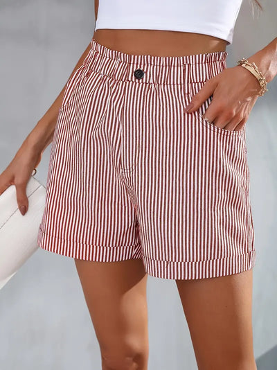 Short en tissu rayé rouge et blanc, taille haute, avec bouton noir, porté par une femme tenant un sac blanc. Mode estivale élégante et décontractée.