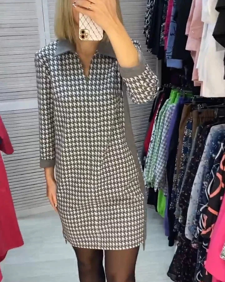 Robe à motif pied-de-poule noir et blanc, manches longues, portée par une femme dans une boutique de vêtements. Mode élégante et tendance.
