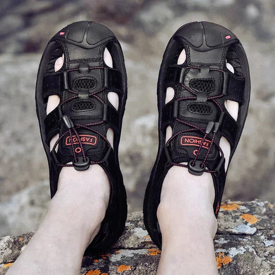 Sandales de randonnée noires pour homme avec lacets élastiques, portées sur un rocher. Chaussures outdoor confortables et respirantes.