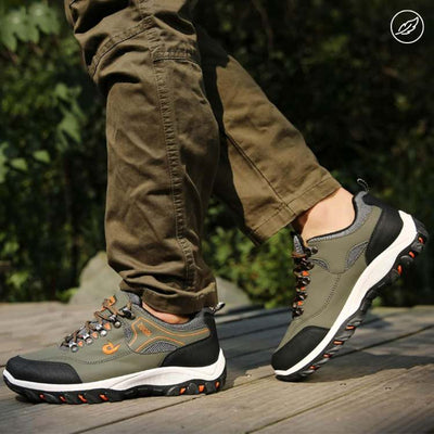 Chaussures de randonnée vertes pour homme sur plancher en bois, pantalon kaki. Confort, durabilité, semelle antidérapante, extérieur, aventure.