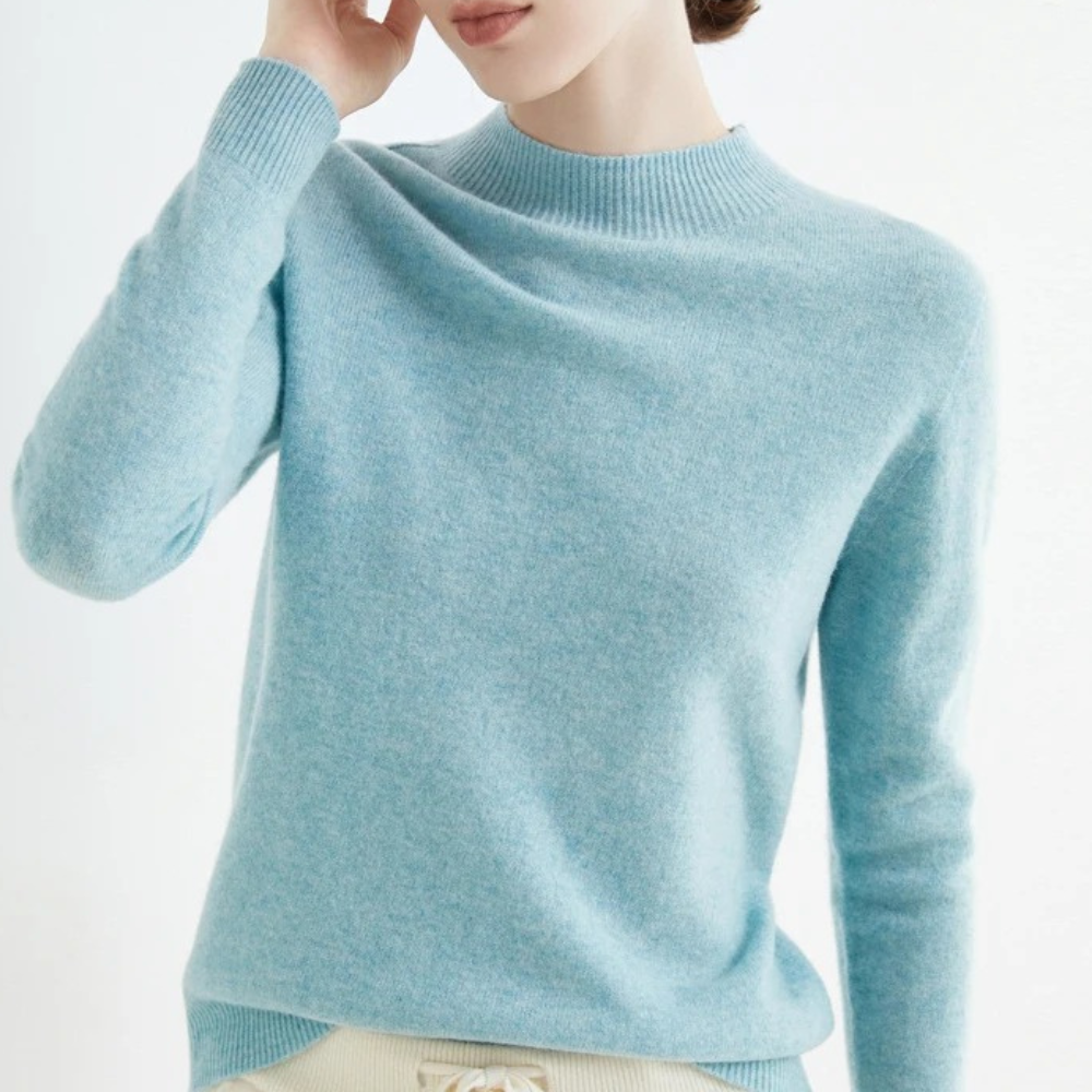 Femme portant un pull en cachemire bleu clair, manches longues, col rond, style élégant et confortable, mode automne-hiver, vêtement doux.