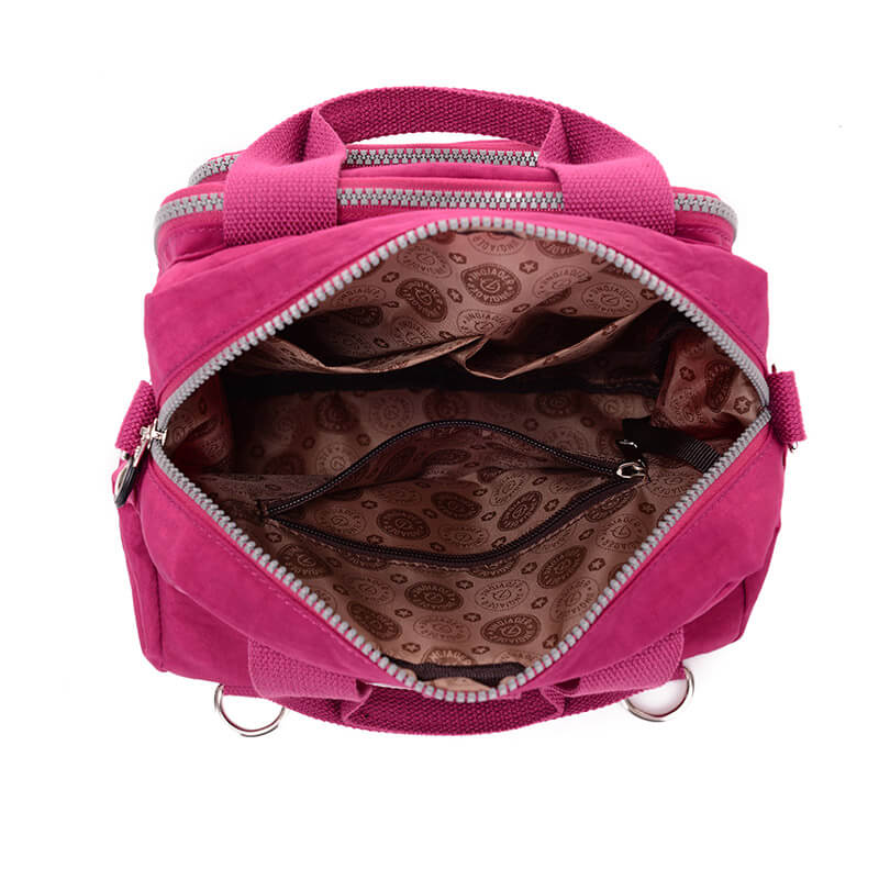 Sac à main rose ouvert avec doublure intérieure à motifs, poches zippées, poignées robustes et fermetures éclair argentées. Accessoire mode femme.