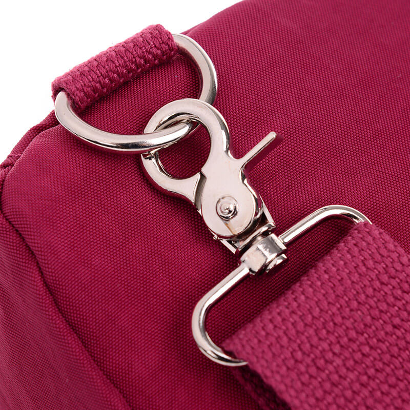 Boucle en métal argenté sur sac bandoulière rose, tissu résistant. Accessoire mode femme, design moderne, idéal pour usage quotidien.
