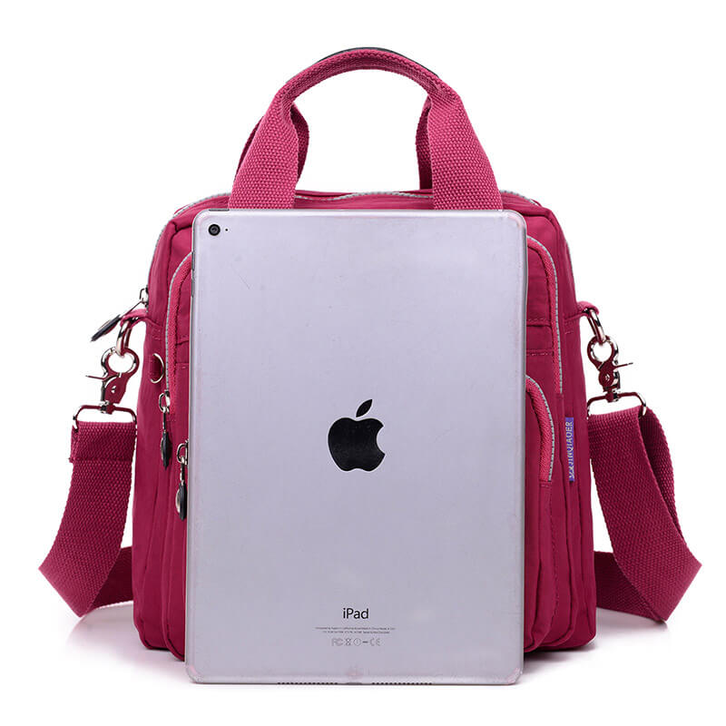 Sac à main rose avec bandoulière, compartiments multiples, et tablette iPad argentée en avant-plan. Accessoire mode femme, pratique et élégant.
